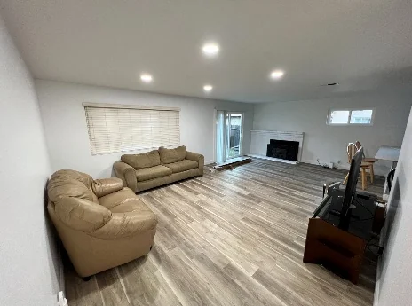 Furnished shared living room with seating, television, fireplace, and dining area